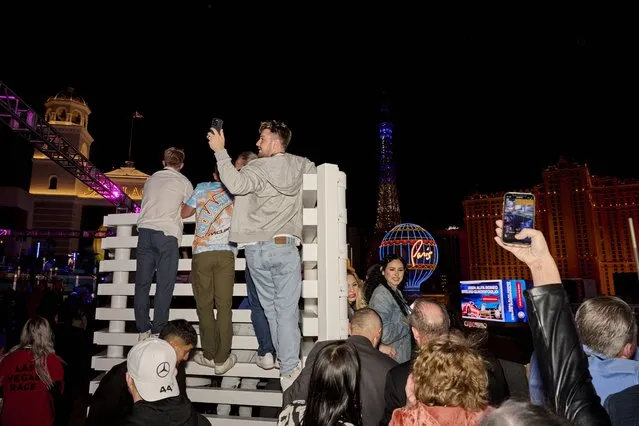 Attendees climb up a wall in attempt to get a better perceive of the race at AIOKA Race Weekend Party at Boulevard Pool in the Cosmopolitan hotel and casino during the Formula 1 Las Vegas Grand Prix in Las Vegas, Nevada on November 18, 2023. (Photo by Bridget Bennett/The Washington Post)