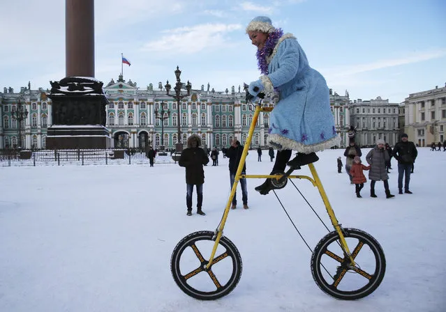 A woman wearing a Snow Maiden costume rides a bike during celebration Old New Year at Dvortsovaya (Palace) Square in St.Petersburg, Russia, Sunday, January 13, 2019. Russian people celebrate so-called Old New Year, which comes on Jan. 14 under the Julian calendar formerly used by Russia and still observed by its Orthodox Church. For most Russians the Old New Year is just a way to prolong the New Year's celebrations. (Photo by Dmitri Lovetsky/AP Photo)