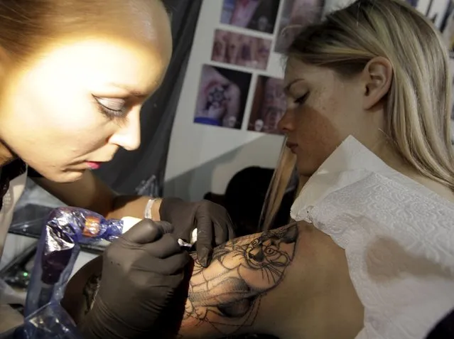 An artist draws a tattoo on a woman's shoulder during a tattoo convention in Ljubljana April 18, 2015. (Photo by Srdjan Zivulovic/Reuters)