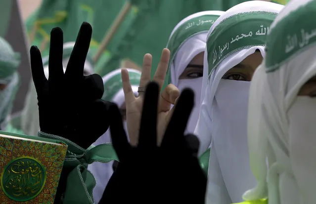 Palestinian students supporters of the Islamic militant movement of Hamas hold the Koran and show three fingers, their electoral number, as they march during the election campaign for students' council  at the Polytechnic University in the West Bank city of Hebron, 20 April 2015. (Photo by Abed Al Haslhamoun/AFP Photo)