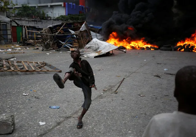 A boy juggles in front of a burning barricade during a protest against the government in the streets of Port-au-Prince, Haiti, February 10, 2019. (Photo by Jeanty Junior Augustin/Reuters)