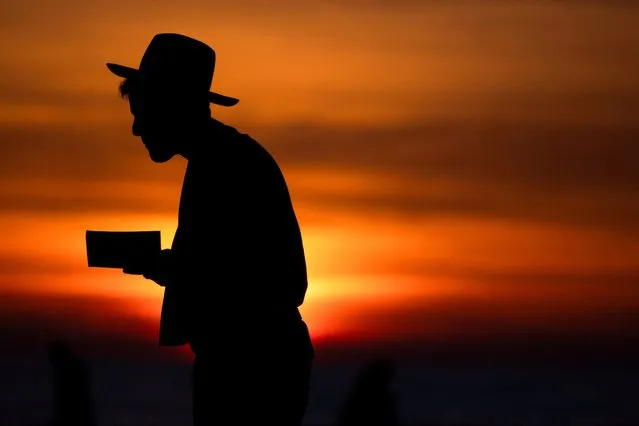 A man prays during sunset, in Ashkelon, Israel on January 8, 2024. (Photo by Amir Cohen/Reuters)