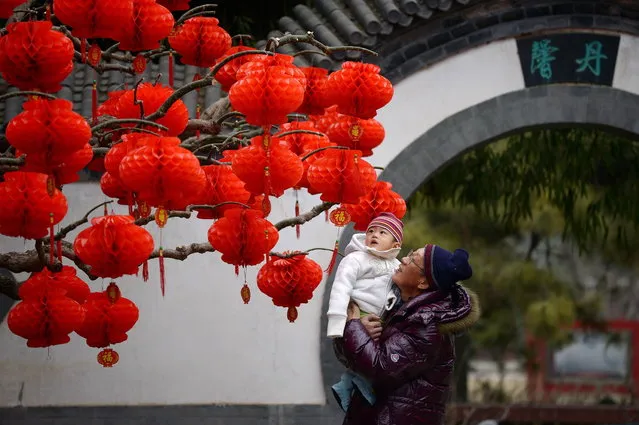 A family visits a park decorated with colorful decals for the upcoming Lunar New Year in Beijing on January 24, 2014. (Photo by Wang Zhao/AFP Photo)