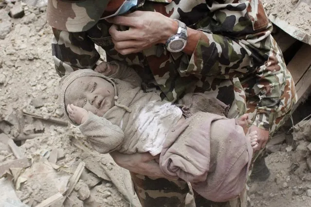 In this Sunday, April 26, 2015, photo taken by Amul Thapasaw and provided by Kathmandu Today, four-month-old baby boy Sonit Awal is held up by Nepalese Army soldiers after being rescued from the rubble of his house in Bhaktapur, Nepal, after Saturday's 7.8-magnitude earthquake shook the densely populated Kathmandu valley. Thapasaw says that when he saw the baby alive after 20 hours of rescue efforts all my sorrow went. (Photo by Amul Thapa/Kathmandu Today via AP Photo)