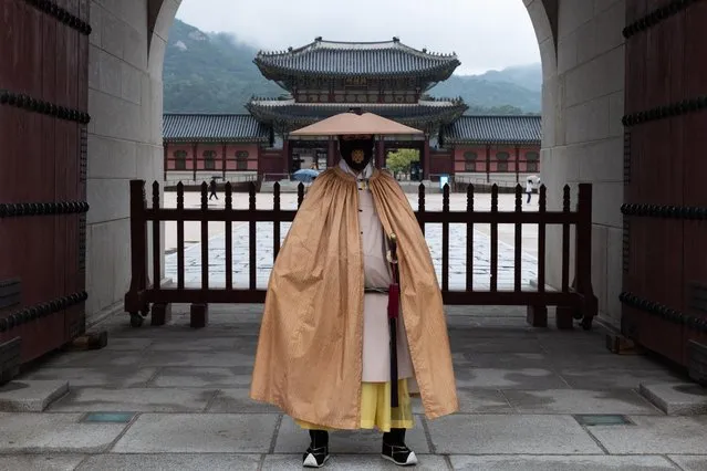 A South Korean official wearing a royal guard raincoat uniform and a face mask, stands before the empty Royal Palace gates at the Gyeongbokgung Palace in Seoul, South Korea, 29 September 2021. The Korea Disease Control and Prevention Agency (KDCA) said on 29 September that the number of coronavirus infections rose by nearly 3,000, raising the total caseload to over 300,000. (Photo by Jeon Heon-Kyun/EPA/EFE)