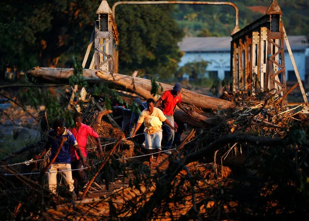 Survivors of cyclone Idai cross a temporary bridge as they arrive at Coppa business centre to receive aid in Chipinge, Zimbabwe, March 26, 2019. (Photo by Philimon Bulawayo/Reuters)