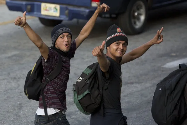 Central American migrants, part of the caravan hoping to reach the U.S. border, poses for photos as they move on a road in Escuintla, Chiapas State, Mexico, Saturday, April 20, 2019. Thousands of migrants in several different caravans have been gathering in Chiapas in recent days and weeks. (Photo by Moises Castillo/AP Photo)