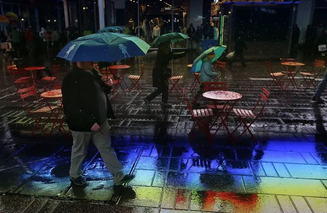 A pedestrian walks through Times Square in a light rain as electronic billboards are reflected on the wet pavement beneath his feet, Wednesday, February 24, 2016, in New York. (Photo by Julie Jacobson/AP Photo)
