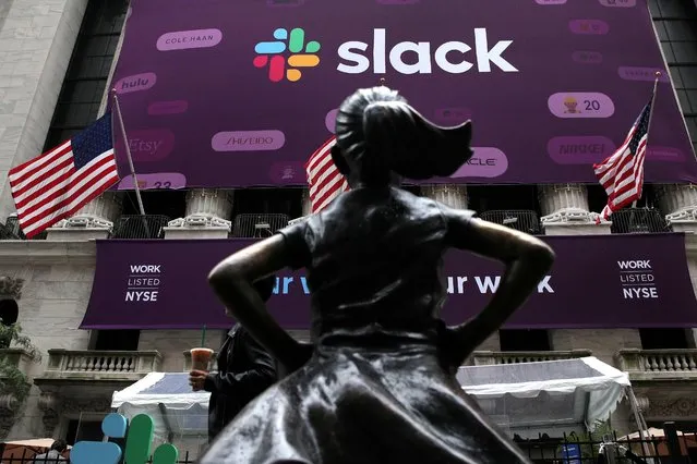 The Slack Technologies Inc. logo is seen behind the “Fearless Girl” statue outside the New York Stock Exchange (NYSE) during the company's direct listing in New York, U.S. June 20, 2019. (Photo by Brendan McDermid/Reuters)