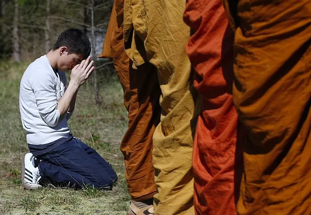 Adisorn Gronski, left, prays while monks from the Atammayatarama Buddhist Monastery in Woodinville chant for victims of the deadly mudslide in Oso, Wash., Tuesday, April 1, 2014, near a road block in Oso. The March 22 mudslide destroyed the rural mountainside community northeast of Seattle. (Photo by Sofia Jaramillo/AP Photo/The Herald)
