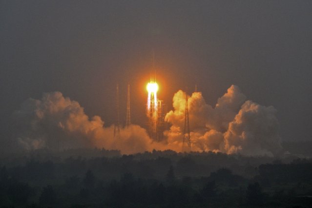 A Long March 5 rocket, carrying the Chang'e-6 mission lunar probe, lifts off as it rains at the Wenchang Space Launch Centre in southern China's Hainan Province on May 3, 2024. (Photo by Hector Retamal/AFP Photo)