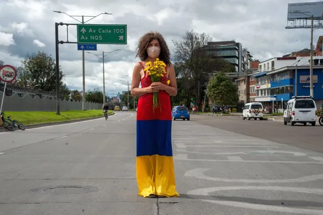 A woman stands in the middle of the road with a dress with the Colombian flag colors upside down and flowers on May 12, 2021, as Bogota, Colombia enters its third week of antigovernment protests against president Ivan Duque Marquez and the deaths that sum up to 40 in Police Brutality cases during the National Strike. (Photo by Chepa Beltran/LongVisual via ZUMA Wire/Rex Features/Shutterstock)