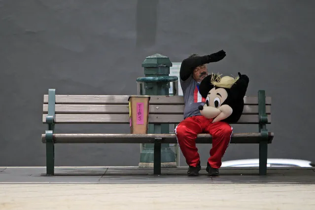 A street performer in a Mickey Mouse costume rests on a bench in Old San Juan, Puerto Rico, Wednesday, July 1, 2015, the day a 11.5% sales tax went into effect, the highest of any U.S. state. (Photo by Ricardo Arduengo/AP Photo)