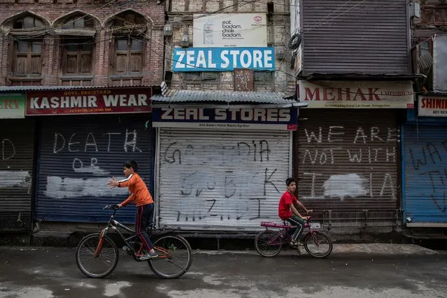 Kashmiri boys cycle in an empty street during restrictions after the scrapping of the special constitutional status for Kashmir by the government, in Srinagar, August 14, 2019. (Photo by Danish Siddiqui/Reuters)