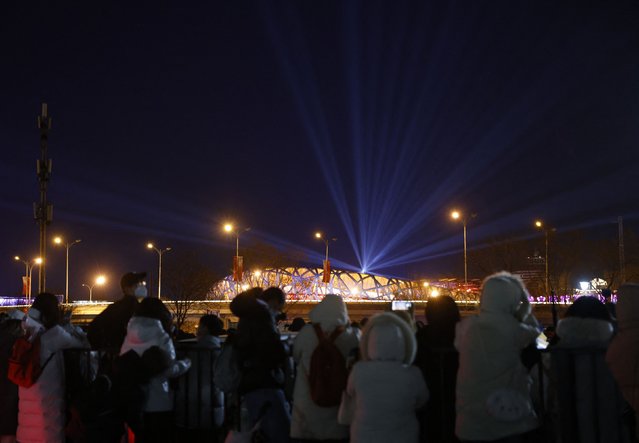 People watch from a parking lot the light show at the National Stadium, also known as the Bird's Nest, during the Beijing 2022 Winter Olympics opening ceremony, in Beijing, China on February 4, 2022. (Photo by Carlos Garcia Rawlins/Reuters)