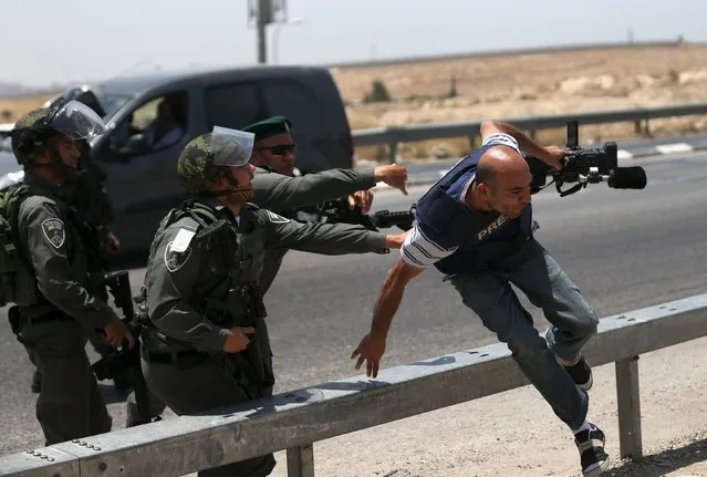 A cameraman runs away from Israeli border policemen during a protest marking the first anniversary of the killing of 16-year-old Palestinian Mohammed Abu Khudair, who was burnt in Jerusalem in a suspected revenge attack for the kidnapping and slaying of three Israeli teens last year, near the West Bank city of Ramallah July 2, 2015. Abu Khudair's abduction and killing sparked violent protests and calls from Palestinians for a new uprising against Israel last year. (Photo by Mohamad Torokman/Reuters)