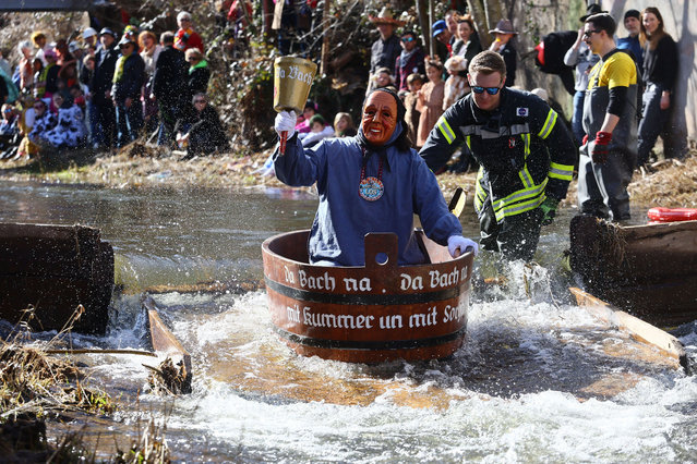 A carnival reveller rides down the Schiltach stream during the “Bach na fahre” (race down the stream) raft contest in Schramberg, Germany on February 20, 2023. (Photo by Wolfgang Rattay/Reuters)