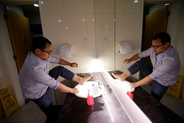 Liu Zhanyu, a client manager at DouMiYouPin, washes his feet at the office's bathroom before going to sleep after finishing work at midnight, in Beijing, China, April 20, 2016. (Photo by Jason Lee/Reuters)