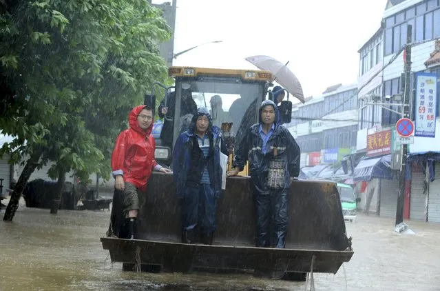 People are carried by a bulldozer as they travel along a flooded street amidst heavy rainfall caused by Typhoon Chan-hom, in Shaoxing, Zhejiang province, China, July 11, 2015. (Photo by Reuters/China Daily)