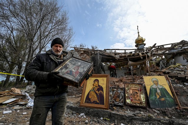 A man carries an Orthodox icon at a site of a church destroyed by a Russian missile strike in Komyshuvakha, Ukraine early hours Sunday, April 16, 2023. (Photo by Reuters/Stringer)