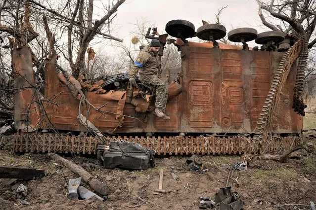 A Ukrainian serviceman jumps from a destroyed Russian fighting vehicle after collecting parts and ammunition in the village of Andriivka, Ukraine, heavily affected by fighting between Russian and Ukrainian forces, Wednesday, April 6, 2022. (Photo by Vadim Ghirda/AP Photo)
