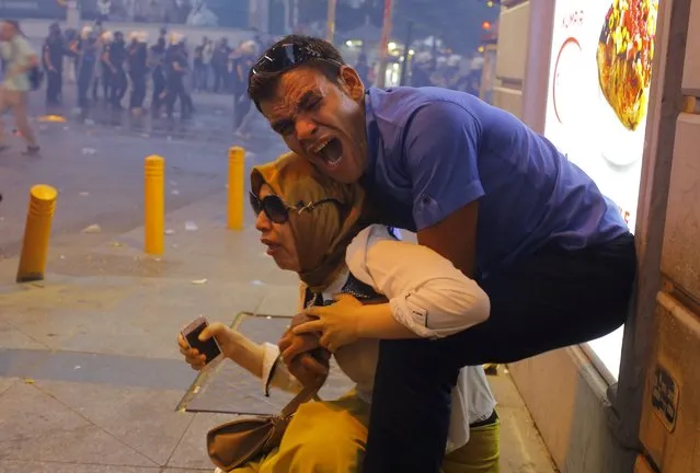 A couple, affected by tear gas used by riot police to disperse demonstrators, reacts in central Istanbul, Turkey, July 20, 2015. (Photo by Huseyin Aldemir/Reuters)