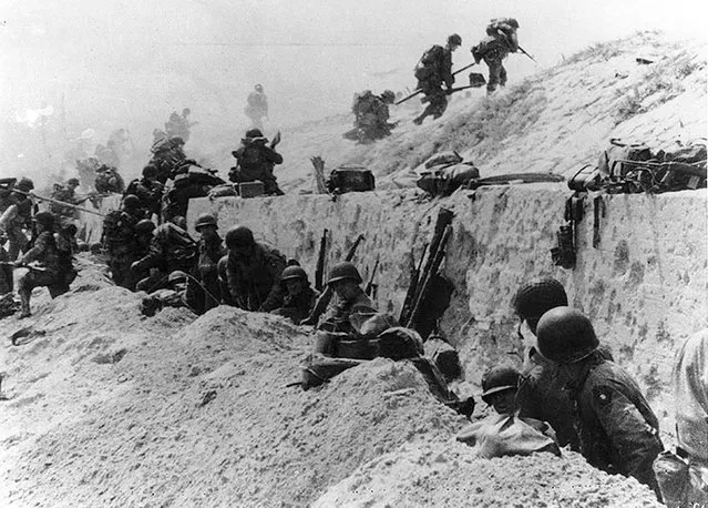 U.S. Army soldiers of the 8th Infantry Regiment, 4th Infantry Division, move out over the seawall on Utah Beach after coming ashore in front of a concrete wall near La Madeleine, France, June 6, 1944. REUTERS/US National Archives/Army Signal Corps Collection