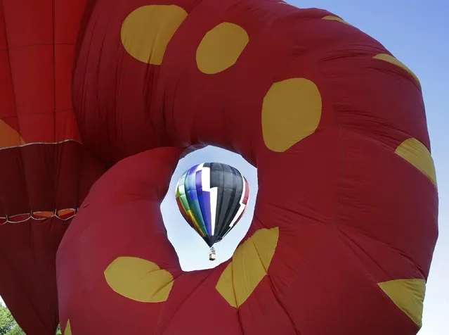 An inflated hot air balloon is seen through the tail of large seahorse character hot air balloon during the 33rd annual QuickChek New Jersey Festival of Ballooning at Solberg Airport Friday, July 24, 2015, in Readington, N.J. (Photo by Mel Evans/AP Photo)