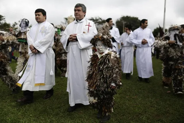 Father Modesto Martinez leads a procession marking the feast day of St Francisco Solano, in Emboscada, Paraguay, Friday, July 24, 2015. There is no record of the Spanish friar, also known as St. Francisco Solanus, in Paraguay, but the devoted believe he is a miracle worker. While he lay dying in a Peruvian convent, the birds would sing to him, perched at his window, and that may be why pledges choose to dress in feathers on his feast day, says Martinez. (Photo by Jorge Saenz/AP Photo)