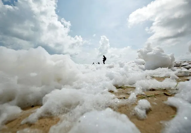 People stand on the Marina beach filled with foam formed from pollution in Chennai, November 29, 2019. (Photo by P. Ravikumar/Reuters)