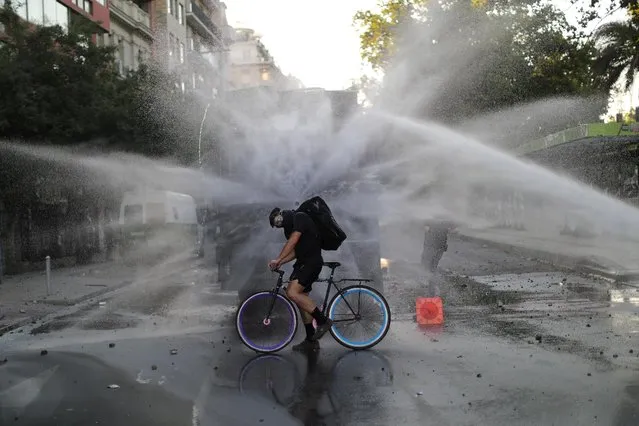 A man on a bicycle is sprayed by a water cannon during a protest against Chile's government in Santiago, Chile on December 5, 2019. (Photo by Pablo Sanhueza/Reuters)