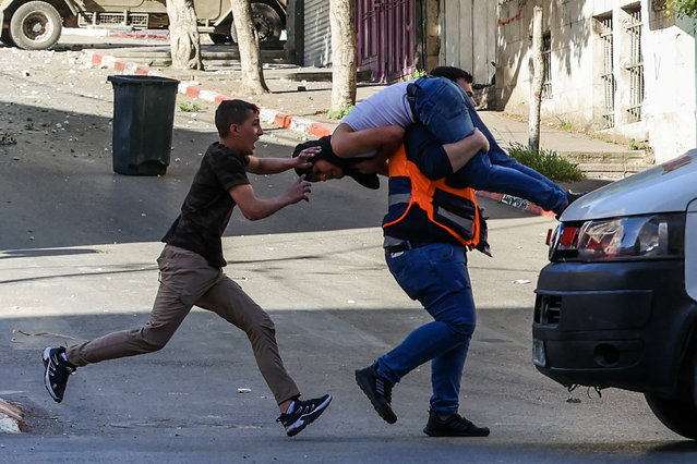 A medic carries an injured man to safety during clashes between Israeli forces and Palestinians following an Israeli army raid in the occupied West Bank city of Nablus on May 4, 2023. Israeli troops killed three people in a raid on the West Bank city of Nablus on May 4, the Palestinian health ministry said. (Photo by Zain Jaafar/AFP Photo)