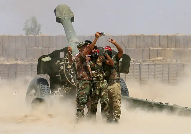 In this Sunday, May 29, 2016 photo, fighters take a selfie while firing artillery during fight against Islamic State militants in Fallujah, Iraq. Iraqi forces this week pushed into the city's southern sections after securing surrounding towns and villages more than 50,000 people are believed to be trapped inside the Sunni majority city, about 65 kilometers (40 miles) west of Baghdad. (Photo by Anmar Khalil/AP Photo)
