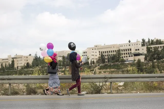 Palestinians carry balloons while making there way to the opening ceremony of Palestinian Museum for Arts and History, in West Bank town of BirZeit, north of Ramallah, 18 May 2016. The $30 million Palestinian Museum contemporary building aims to redefine the Palestinian art, history and culture. (Photo by Atef Safadi/EPA)