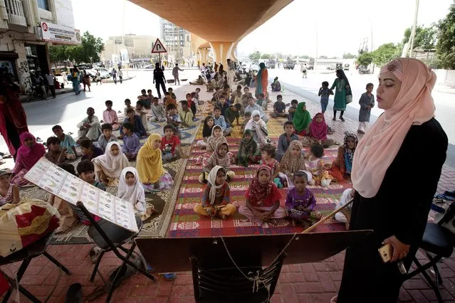 Pakistani volunteer Syeda Anfas Zaidi teaches students at a make shift school under a bridge in Karachi, Pakistan, Wednesday, May 25, 2016. Over 100 children have been attending the school, established under a bridge, some two months ago. The idea of initiating education for poor children was in memory of dozens of children who were shot dead by terrorists at an Army Public School in Peshawar. (Photo by Shakil Adil/AP Photo)