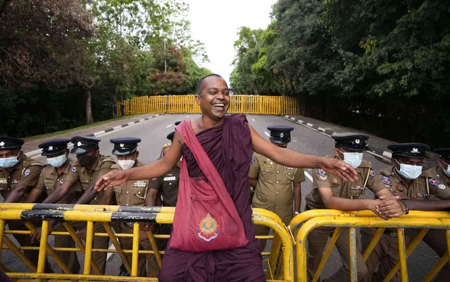 A Sri Lankan Buddhist monk sitting on a police barricade cracks a joke about lawmakers during a protest outside parliament in Colombo, Sri Lanka, Thursday, May 5, 2022. Sri Lanka’s beleaguered government won a key vote in Parliament on Thursday as a ruling coalition-backed candidate was elected deputy speaker, despite growing public pressure on the government amid the worst economic crisis in decades. (Photo by Eranga Jayawardena/AP Photo)