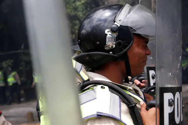 A riot police officer reacts to the tear gas effects as they clash with demonstrators during a protest called by university students against Venezuela's government in Caracas, Venezuela, June 9, 2016. (Photo by Carlos Garcia Rawlins/Reuters)
