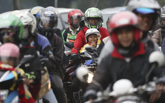 People ride motorcycles in Bekasi on the outskirts of Jakarta, Indonesia, Thursday,  June 22, 2017. The mass exodus out of the capital and other major cities in the world's most populous Muslim country is underway as millions are heading home to their villages to celebrate Eid al-Fitr holiday on June 25. The holiday marks the end of the holy fasting month of Ramadan. (Photo by Achmad Ibrahim/AP Photo)