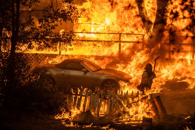 A Firefighter walks in a evacuated home in flames at El Cariso Village as the Airport Fire burns on September 10, 2024 in Lake Elsinore, California. The fast-moving Airport Fire that started on September 9 in Orange County grew up to more than 10,000 acres by this afternoon, fire officials said. (Photo by Apu Gomes/Getty Images)