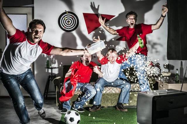 Four young adult men friends watching football on television: Goal!. (Photo by ilbusca/Getty Images)