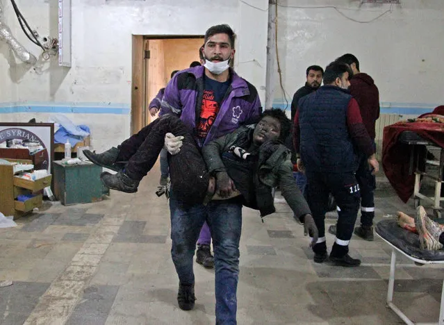 A member of the Syrian Violet Oragnization carries an injured boy at a makeshift hospital following a regime air strike on a vegetable market in Syria's last major opposition bastion of Idlib on January 15, 2020. Regime air strikes on Syria's last major opposition bastion killed at least nine civilians, striking bustling areas of Idlib city despite a fresh Russian-sponsored truce, a war monitor said. (Photo by Abdulaziz Ketaz/AFP Photo)