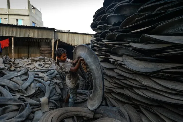 A young labourer handles pieces of an old tyre in Dhaka, Bangladesh on September 19, 2019. (Photo by Munir Uz Zaman/AFP Photo)