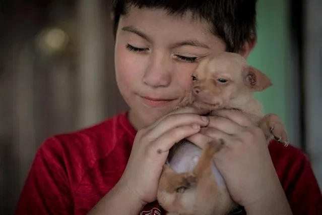 Eight-year-old Jeremiah Lennon hugs his puppy named “Peanut” at his home on Saturday, May 28, 2022, in Uvalde, Texas. The third grader had been in classroom 112, just next to the rooms where the shooter holed up. The 15 kids in his class sat on the ground in the corner, as quiet as they could be, he said. The gunman tried to get in but the door was locked. Jeremiah said he was mad at first, because they were missing recess. He was also terrified: “I was scared I would get shot, my friends would get shot”. (Photo by Wong Maye-E/AP Photo)