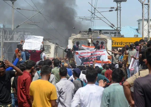 Protesters shout slogans after setting a train on fire during a demonstration against the government's new 'Agnipath' recruitment scheme for the army, navy, and air forces at a railway station in Secunderabad on June 17, 2022. (Photo by Noah Seelam/AFP Photo)