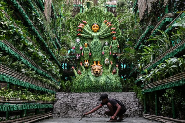 An artisan gives a finishing touch to a Durga Puja “Pandal” (temporary place for worship), where more than 8000 natural plants are used for the decoration to create awareness about mother nature, next to an idol of the Hindu Goddess Durga, as a part of the “Durga Puja” festival in Kolkata on October 5, 2024. (Photo by Dibyangshu Sarkar/AFP Photo)