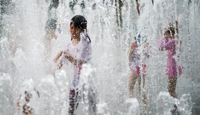 A young girl plays in a fountain to keep cool on a hot summers day in Shanghai on July 23, 2014. (Photo by Johannes Eisele/AFP Photo)