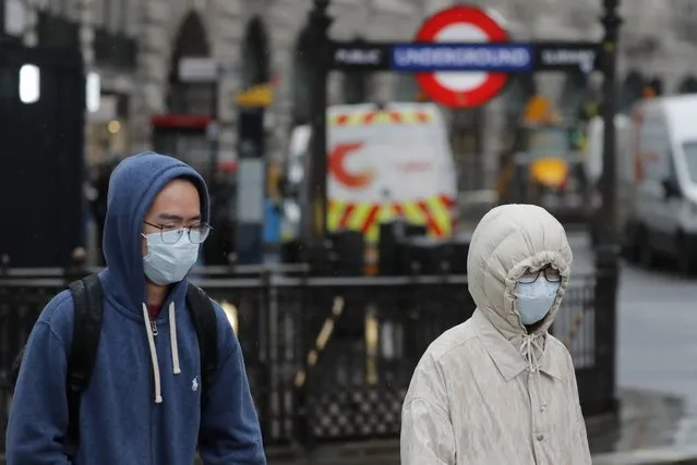 Pedestrians wear face masks as they walk at Piccadilly Circus main tourist destination in central London, as the public are asked to take precautions to protect themselves from the COVID-19 Coronavirus outbreak,  Thursday, March 5, 2020. (Photo by Frank Augstein/AP Photo)
