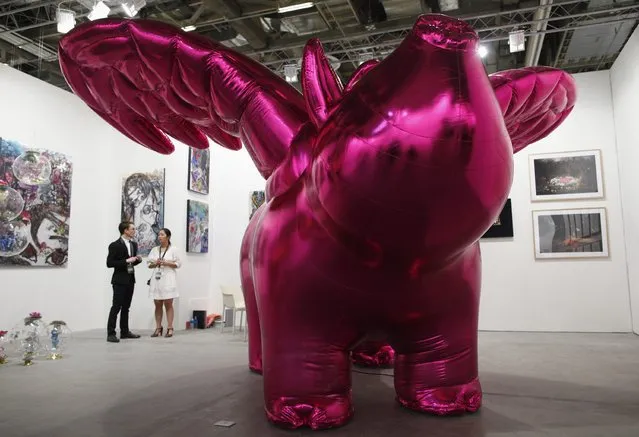 Gallery staff stand next to “Love Me”, an inflatable pig with wings, by South Korean artist Choi Jeong-hwa, during a preview of the Art Stage Singapore at Marina Bay Sands Convention and Exhibition Center in Singapore January 15, 2014. (Photo by Edgar Su/Reuters)