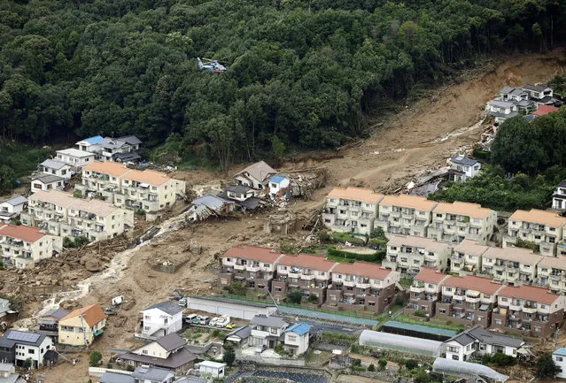 In this aerial photo, a rescue helicopter hovers  over an area devastated by a massive landslide in Hiroshima, western Japan, Wednesday, August 20, 2014. A several people died and at least a dozen are missing after rain-sodden hills in the outskirts of Hiroshima gave way early Wednesday in several landslides. (Photo by AP Photo/Kyodo News)