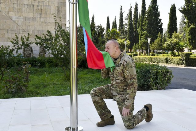 In this photo provided by Azerbaijan's Presidential Press Office on Sunday, October 15, 2023, Azerbaijani President Ilham Aliyev kisses a Azerbaijani National Flag in the city of Aghdara also known as Mardakert to Armenians in Aghdara, Azerbaijan. Aliyev has raised his nation's flag over the capital of Karabakh in a ceremony reaffirming Baku's control of the disputed region. (Photo by Azerbaijani Presidential Press Office via AP Photo)